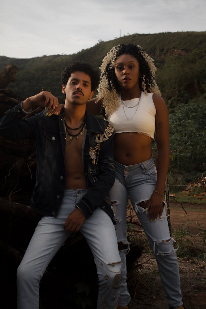 A fashionable couple poses outdoors in casual wear, embracing a rugged style.